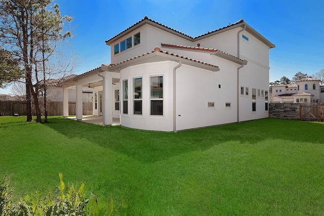 back of house with a fenced backyard, stucco siding, a tiled roof, a patio area, and a lawn