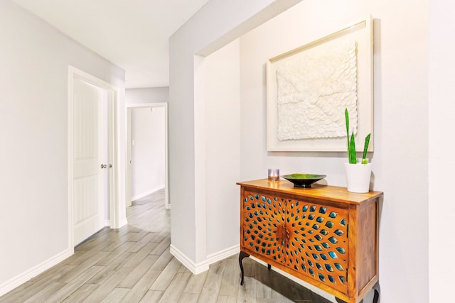 corridor featuring baseboards and light wood-type flooring