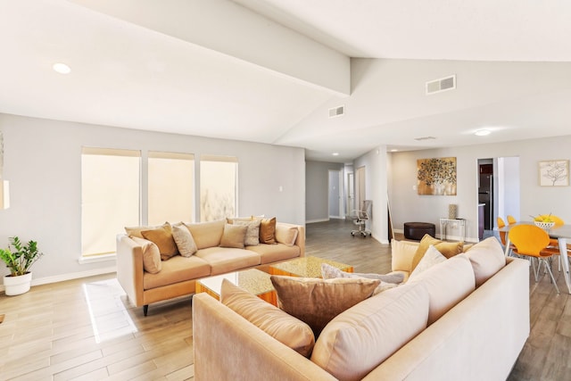 living area featuring lofted ceiling, light wood-style floors, visible vents, and baseboards