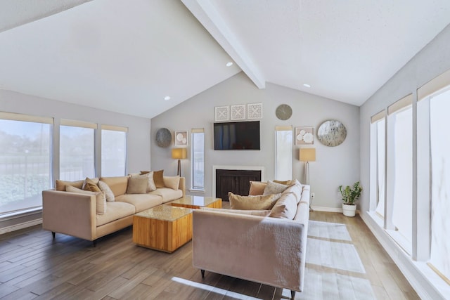 living room featuring a fireplace, lofted ceiling with beams, baseboards, and wood finished floors