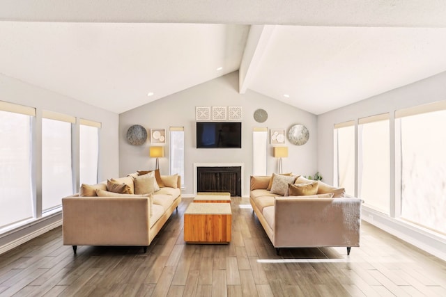 living area featuring baseboards, a fireplace, wood finished floors, and vaulted ceiling with beams