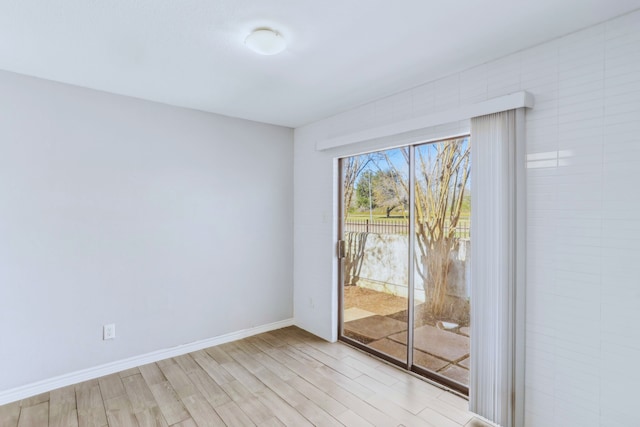 spare room with baseboards and light wood finished floors