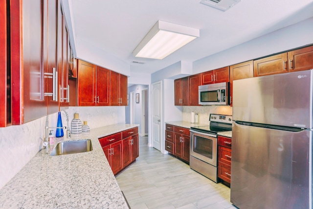 kitchen with a sink, stainless steel appliances, reddish brown cabinets, and decorative backsplash