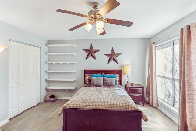 bedroom featuring a ceiling fan, light wood-style floors, baseboards, and a closet