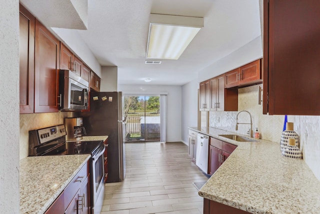 kitchen with reddish brown cabinets, appliances with stainless steel finishes, and a sink