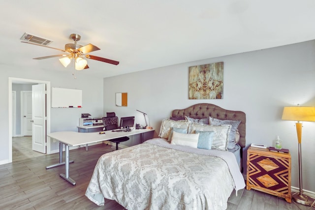 bedroom featuring ceiling fan, wood finished floors, visible vents, and baseboards