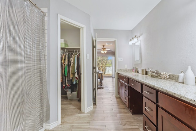 bathroom with visible vents, a shower with curtain, wood finished floors, ceiling fan, and vanity