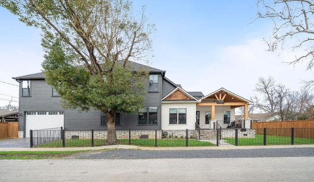 view of front of home with an attached garage, driveway, and a fenced front yard