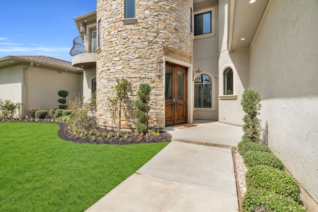 doorway to property featuring a yard, stone siding, and stucco siding