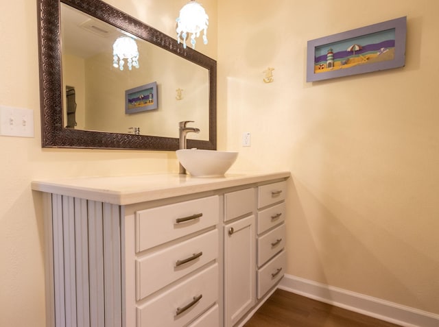 bathroom featuring visible vents, vanity, baseboards, and wood finished floors