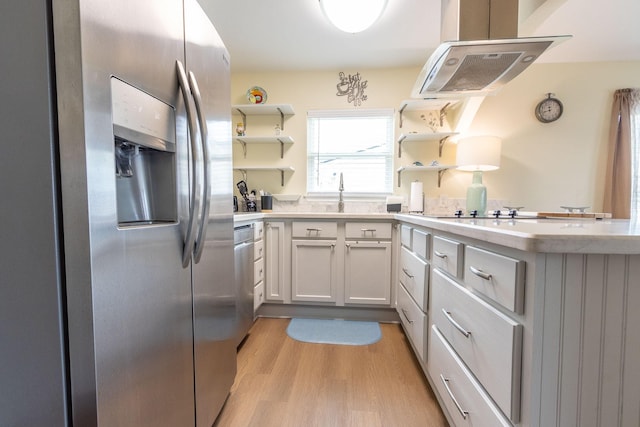 kitchen featuring ventilation hood, open shelves, light wood-style flooring, light countertops, and appliances with stainless steel finishes