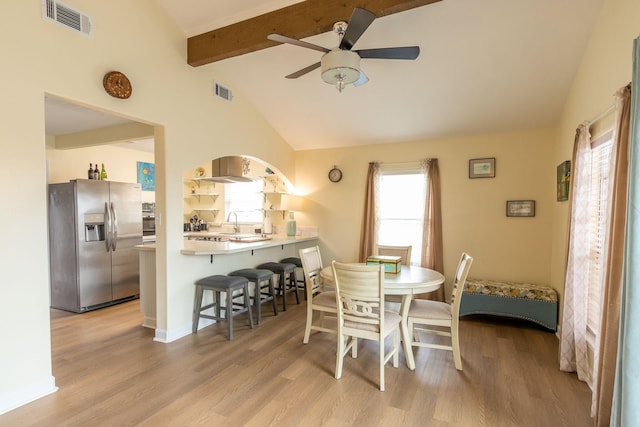 dining room featuring light wood-style flooring, vaulted ceiling with beams, a ceiling fan, and visible vents