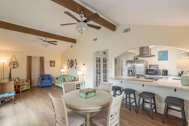 dining area featuring visible vents, ceiling fan, beamed ceiling, light wood-type flooring, and arched walkways