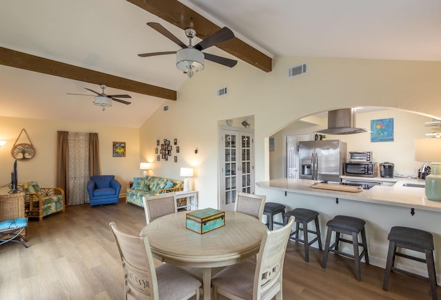 dining space featuring visible vents, beamed ceiling, ceiling fan, and wood finished floors