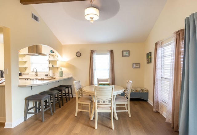 dining area with visible vents, wood finished floors, arched walkways, baseboards, and vaulted ceiling