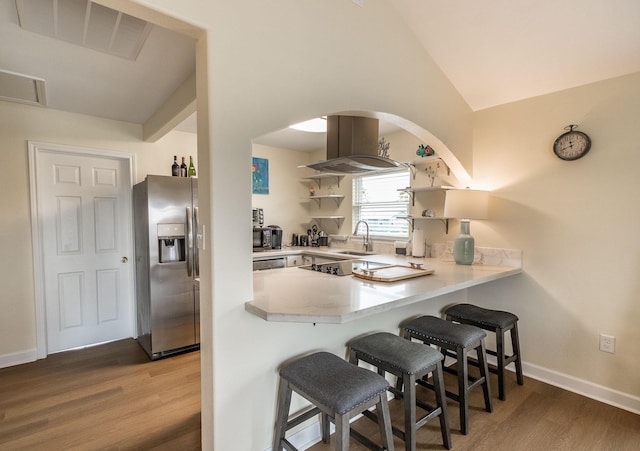 kitchen featuring visible vents, stainless steel refrigerator with ice dispenser, island exhaust hood, a peninsula, and light countertops