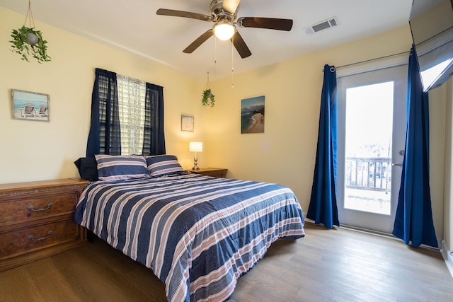 bedroom featuring a ceiling fan, access to exterior, wood finished floors, and visible vents