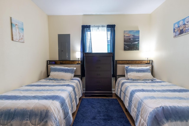 bedroom with electric panel and wood finished floors