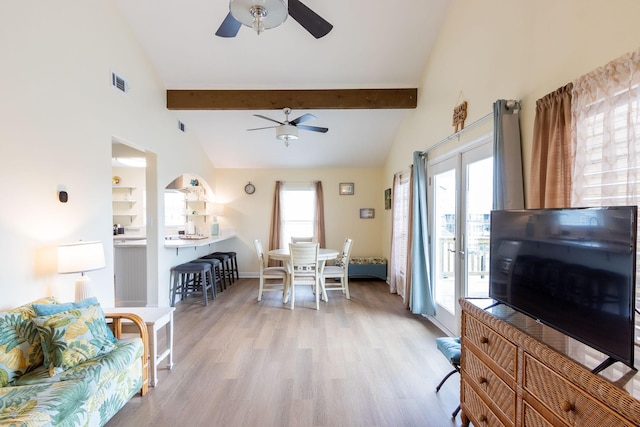 living room with light wood-type flooring, visible vents, beam ceiling, and ceiling fan