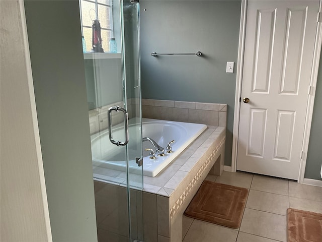 bathroom featuring tile patterned floors, a bath, baseboards, and a shower stall