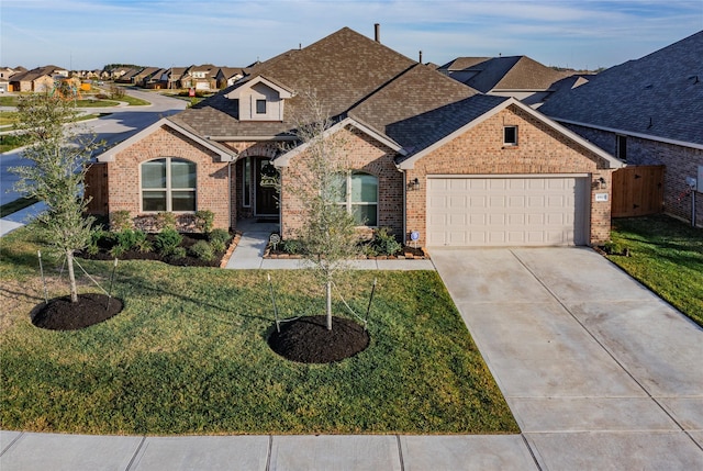 view of front of home with brick siding, an attached garage, driveway, and a front lawn