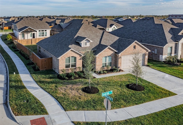 view of front of home featuring fence, a residential view, a shingled roof, concrete driveway, and brick siding