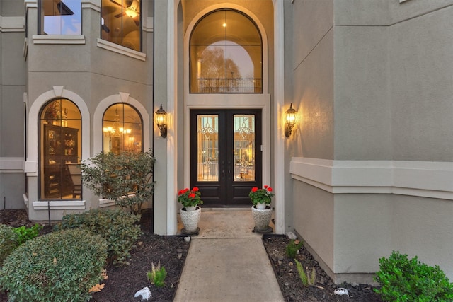 view of exterior entry featuring french doors and stucco siding