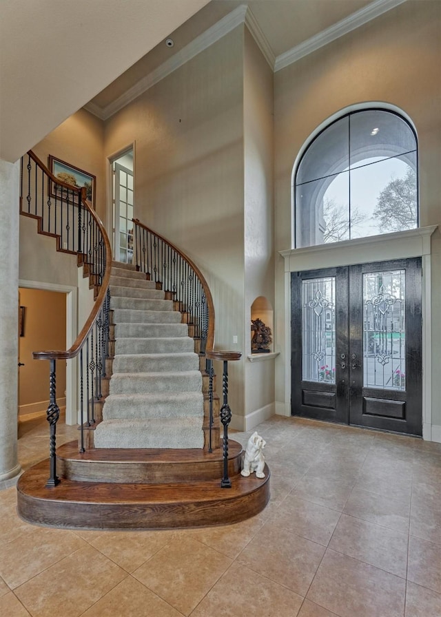 tiled entrance foyer with baseboards, stairway, ornamental molding, french doors, and a towering ceiling