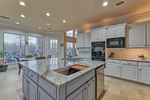 kitchen featuring black appliances, tasteful backsplash, visible vents, and a sink