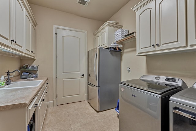 washroom with visible vents, independent washer and dryer, a sink, cabinet space, and light tile patterned flooring