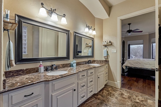 ensuite bathroom with a sink, double vanity, ornamental molding, and a ceiling fan