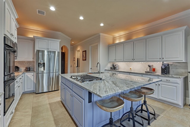 kitchen with visible vents, a center island with sink, light tile patterned floors, arched walkways, and stainless steel appliances