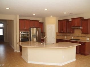 kitchen with a sink, recessed lighting, ventilation hood, appliances with stainless steel finishes, and a large island with sink