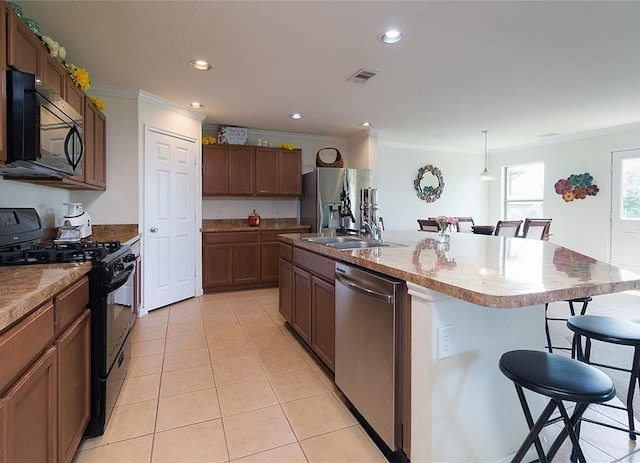 kitchen with light tile patterned floors, visible vents, a sink, black appliances, and a kitchen bar