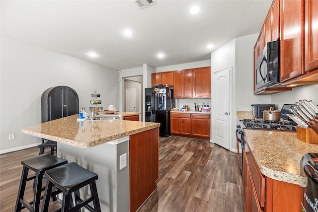 3615 Hawley Creek Dr, Spring, TX 77386 - kitchen featuring black appliances, a kitchen bar, dark wood-type flooring, light countertops, and recessed lighting