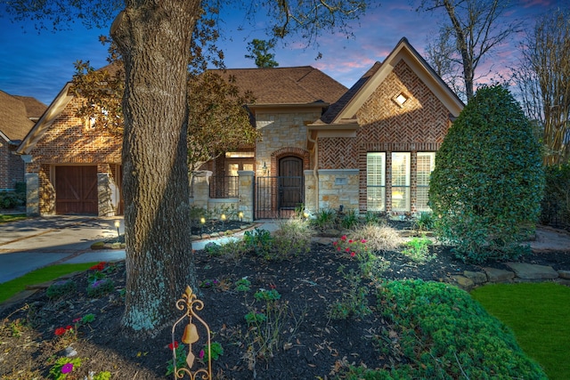 view of front of home featuring an attached garage, stone siding, and driveway