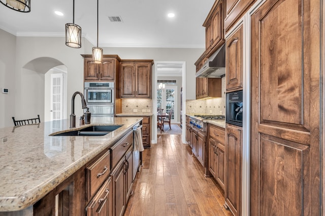 kitchen with visible vents, arched walkways, ornamental molding, under cabinet range hood, and appliances with stainless steel finishes