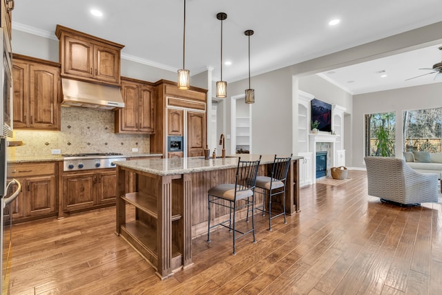 kitchen featuring under cabinet range hood, open shelves, light wood-type flooring, and open floor plan