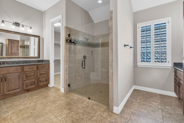 full bath featuring lofted ceiling, a stall shower, vanity, baseboards, and a spacious closet