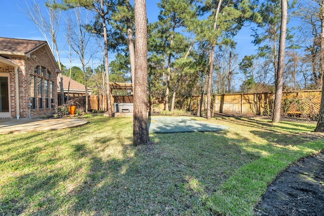 view of yard with a fenced backyard, a hot tub, and a patio