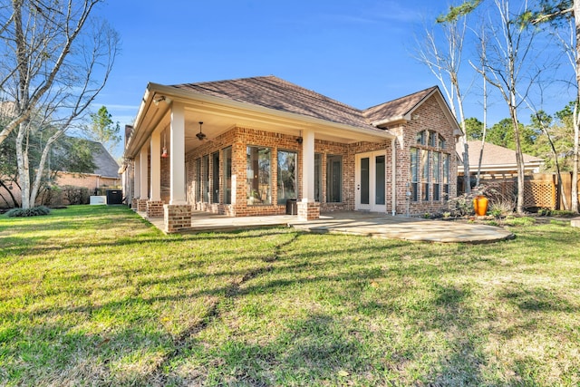 back of property featuring a patio area, fence, brick siding, and a lawn