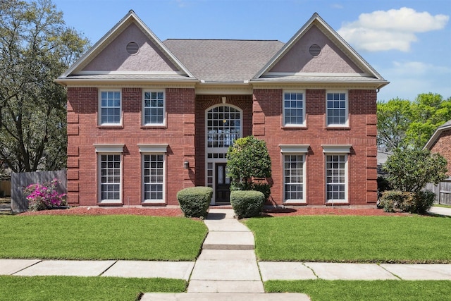 view of front of property with brick siding, a front lawn, and fence