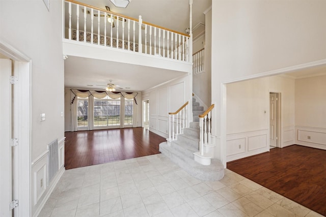 foyer featuring stairs, visible vents, a ceiling fan, and a decorative wall