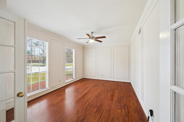 spare room featuring a decorative wall, wood finished floors, visible vents, and ceiling fan