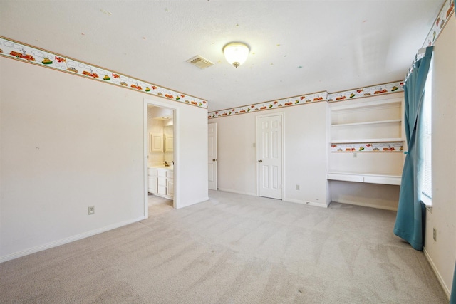 unfurnished bedroom featuring light carpet, visible vents, connected bathroom, and baseboards