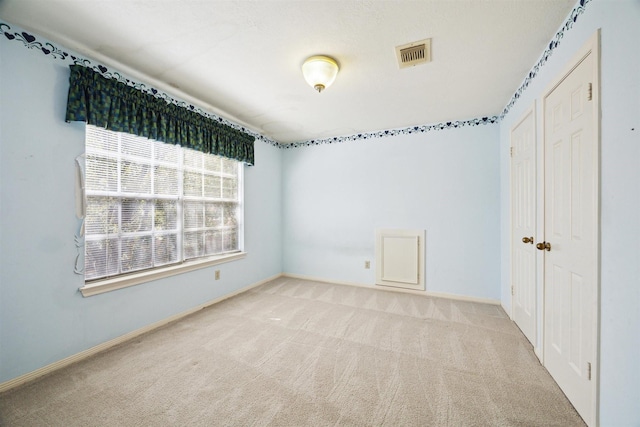 carpeted spare room with visible vents and baseboards