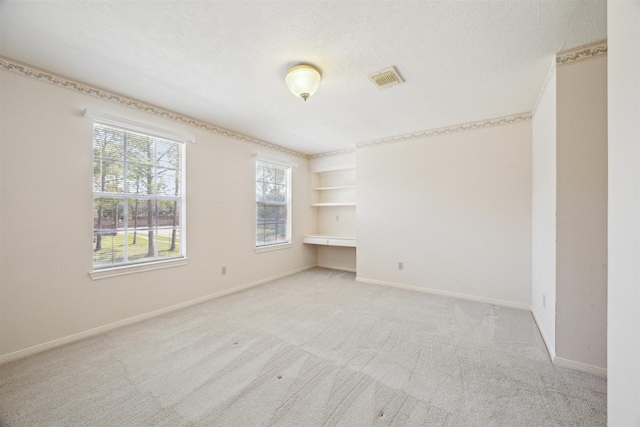 empty room featuring visible vents, light colored carpet, baseboards, and a textured ceiling