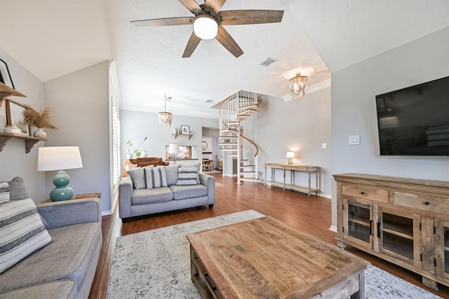 living room featuring visible vents, crown molding, stairs, ceiling fan with notable chandelier, and wood finished floors