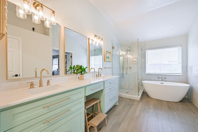 full bathroom featuring a sink, wood finished floors, a shower stall, double vanity, and lofted ceiling