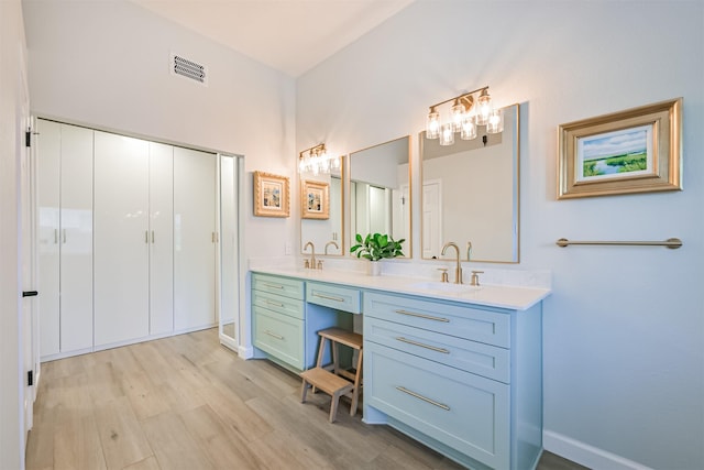 full bathroom with wood finished floors, baseboards, visible vents, double vanity, and a sink